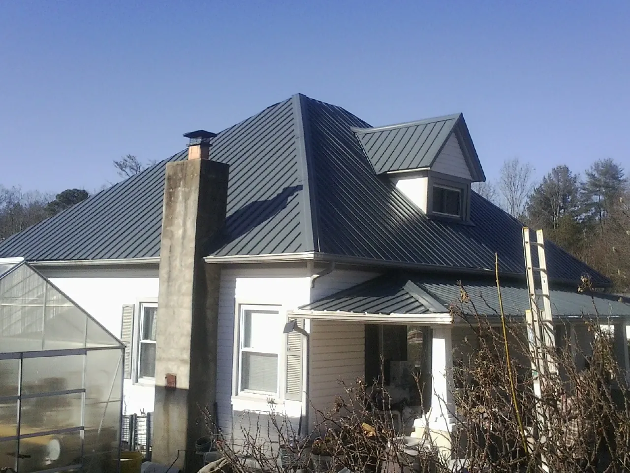Dark blue standing seam metal roof on a white farmhouse with dormer — Slate & Tile Roof Repair by Roofing Brothers in Alleyton
