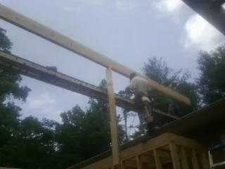 Carpenter setting a ridge beam over a new addition frame — Ice Dam Removal by Roofing Brothers in Alleyton