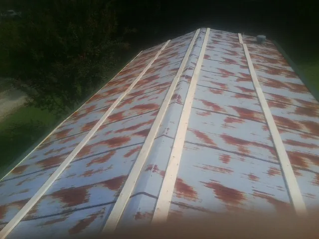 Rusted metal roof panels with new wood purlins before replacement — Storm Damage Roof Repair in Alleyton by Roofing Brothers