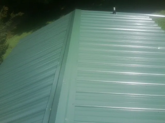 New green metal panels meeting at the ridge of a roof — Flat Roof Repair work by our crew in Alleyton