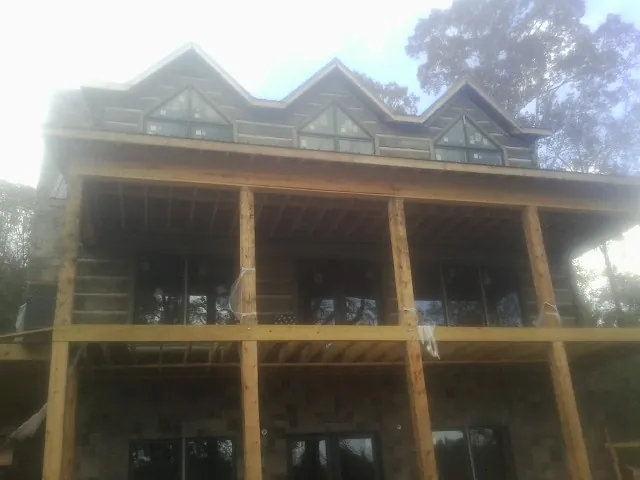 Dormers and porch framing on a large log home under construction — Roof Coating work by our crew in Alleyton