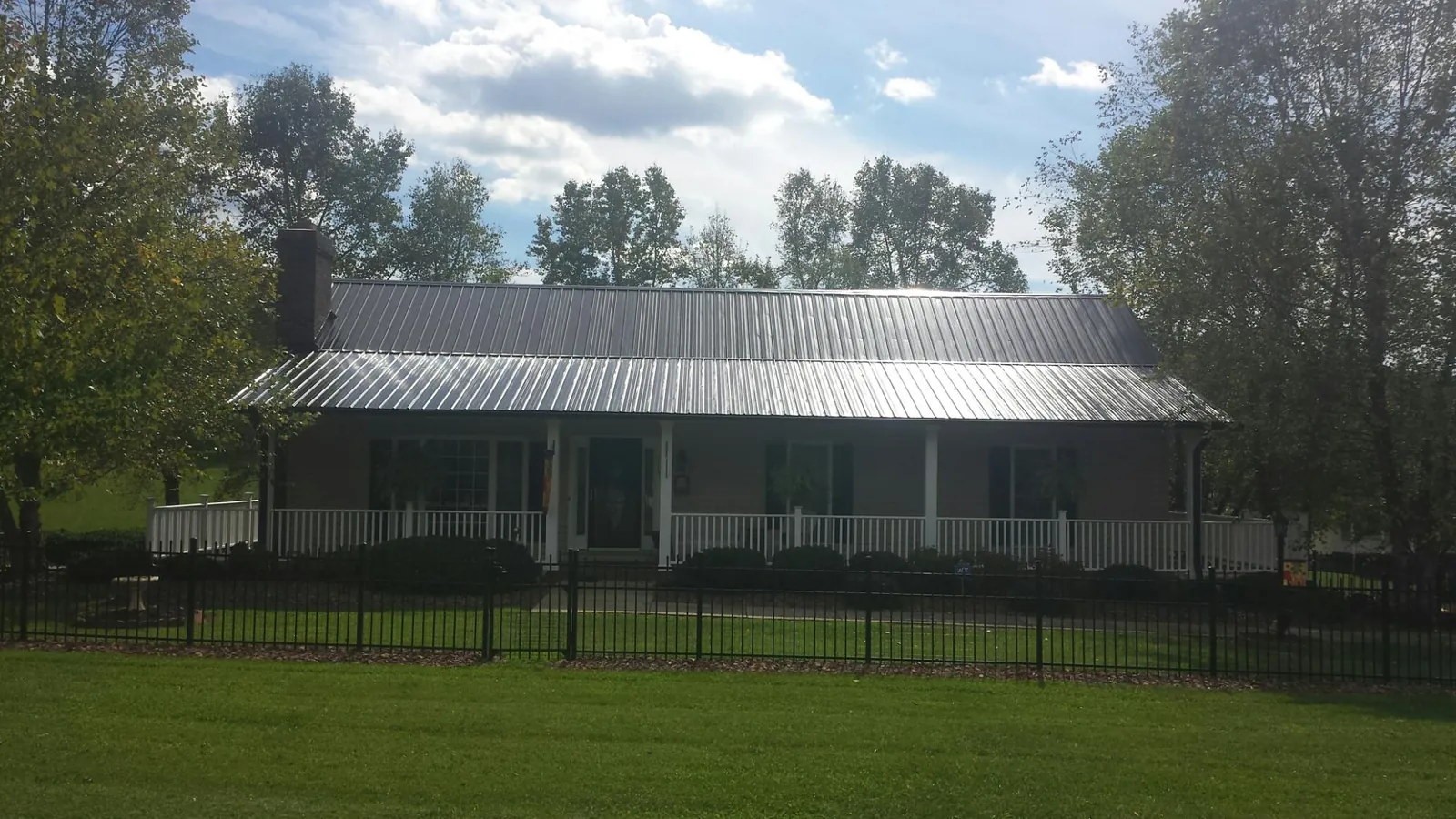 Gray metal roof on a brick ranch with a full width front porch — Gutter Guard Installation work by our crew in Alleyton
