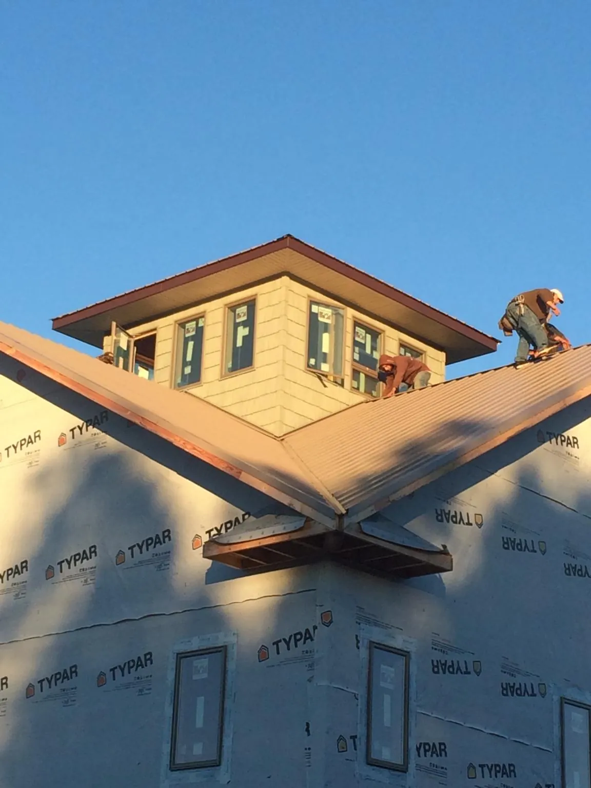 Roofers working around a rooftop cupola on a new metal roof at sunset — Roof Waterproofing in Alleyton by Roofing Brothers